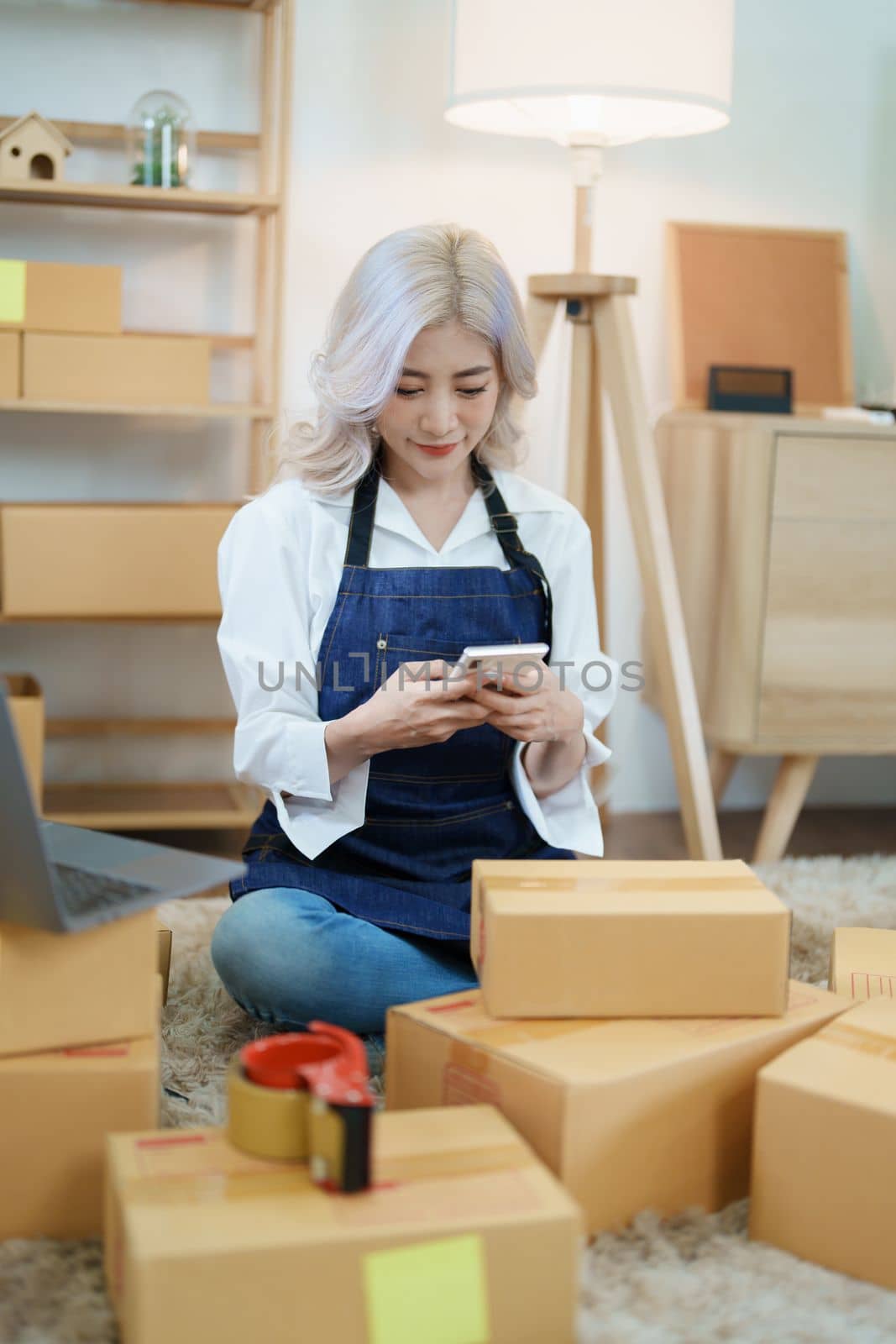 Starting small business entrepreneur of independent Asian woman smiling using computer laptop with cheerful success of online marketing package box items and SME delivery concept.