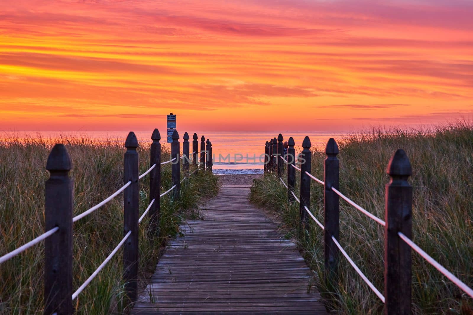 Image of Boardwalk path leading directly to Maine east coast ocean view during stunning orange and red sunrise