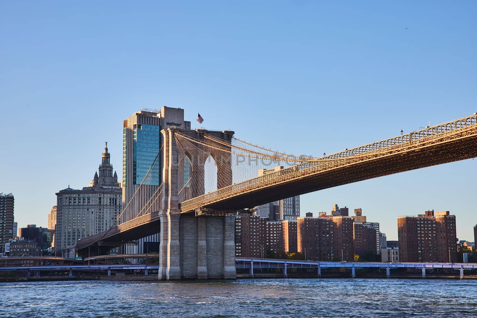 Image of Brooklyn Bridge in New York City with city skyline in background along river