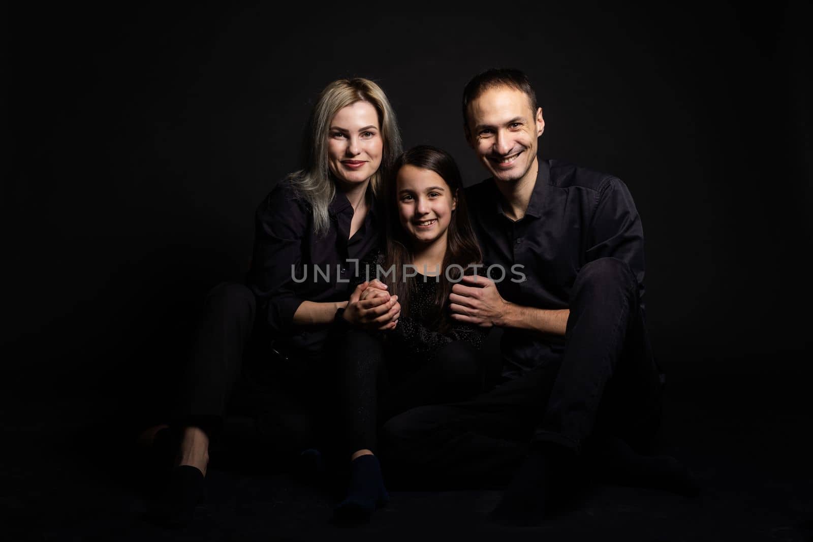 cute little girl and her beautiful young parents looking at camera and smiling.