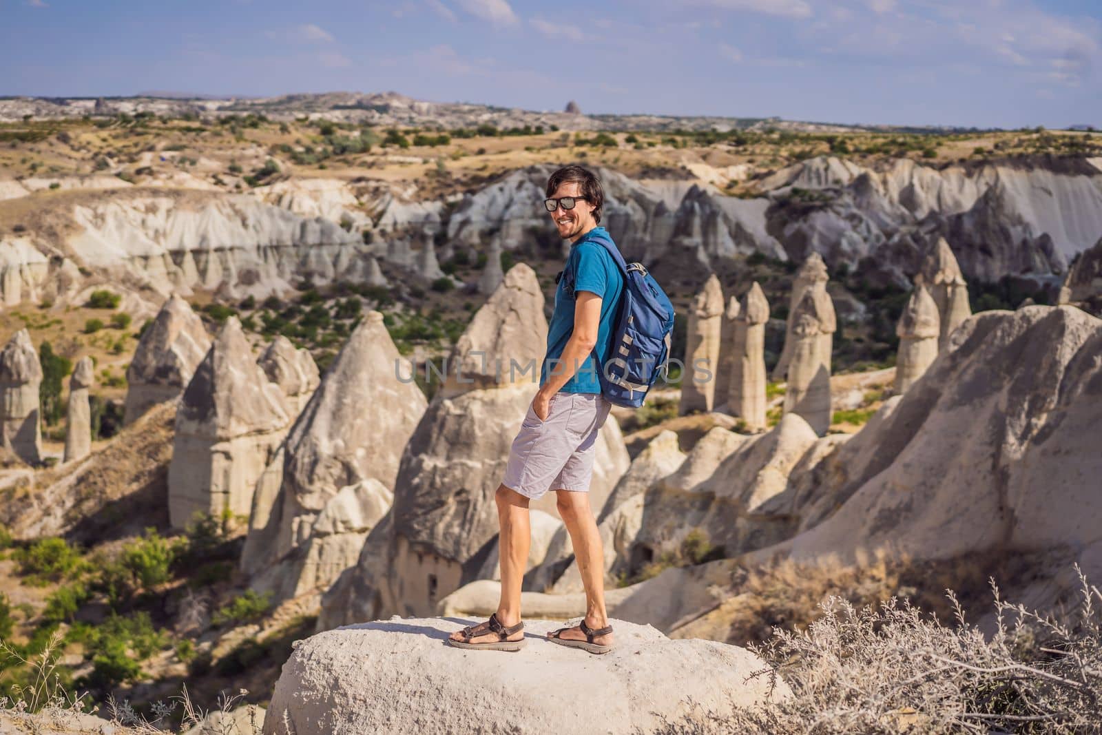 Young man exploring valley with rock formations and fairy caves near Goreme in Cappadocia Turkey.