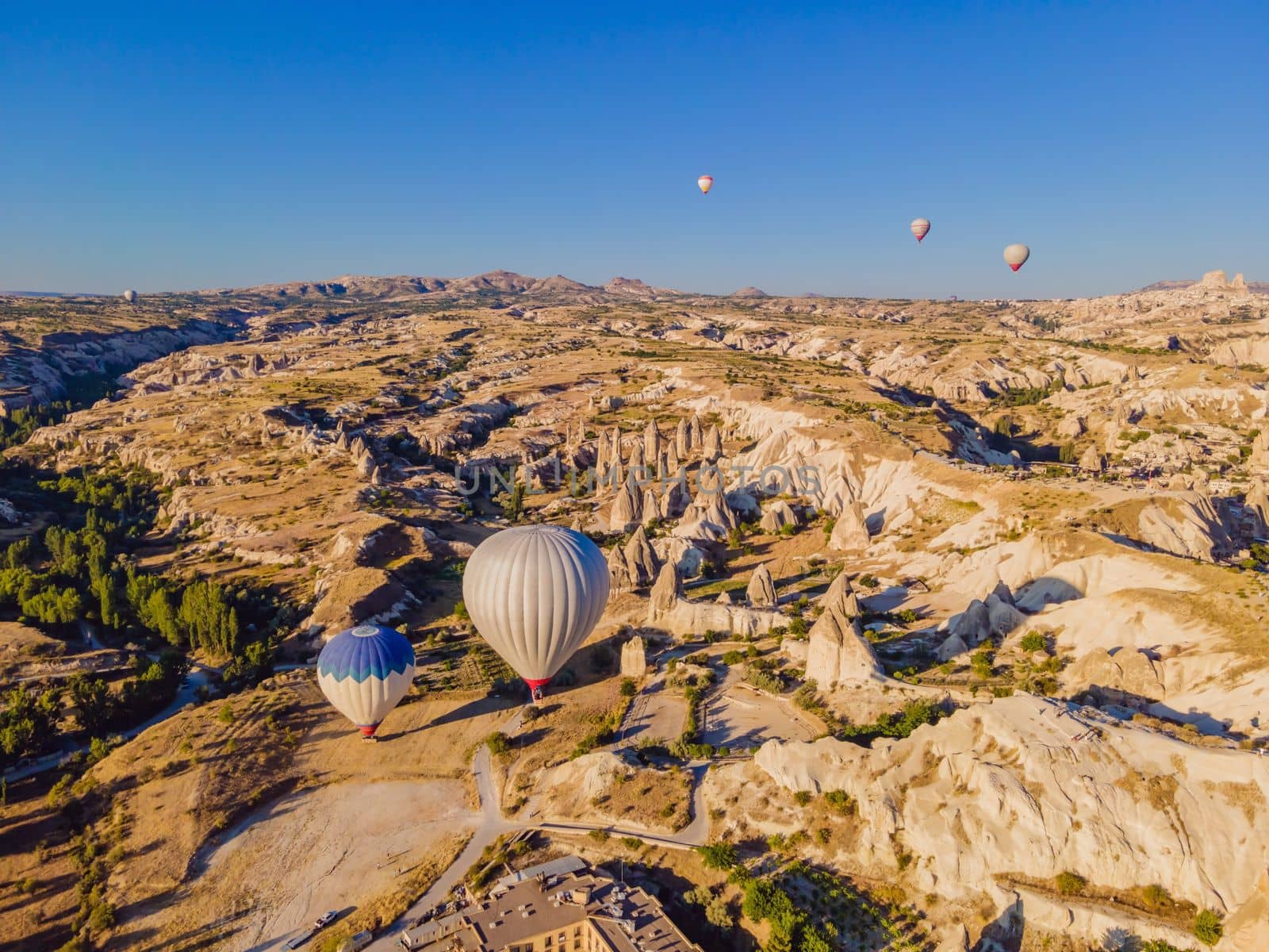 Colorful hot air balloons flying over at fairy chimneys valley in Nevsehir, Goreme, Cappadocia Turkey. Spectacular panoramic drone view of the underground city and ballooning tourism. High quality by galitskaya