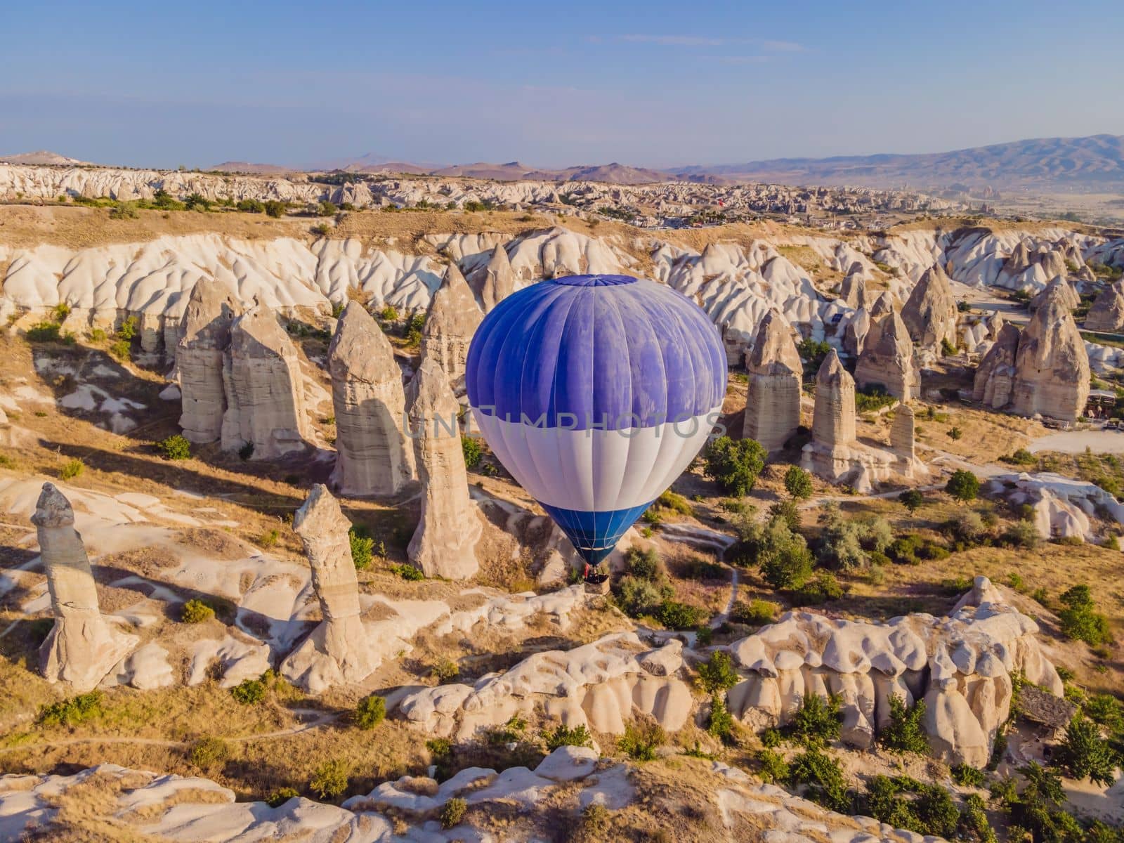 Colorful hot air balloons flying over at fairy chimneys valley in Nevsehir, Goreme, Cappadocia Turkey. Spectacular panoramic drone view of the underground city and ballooning tourism. High quality by galitskaya