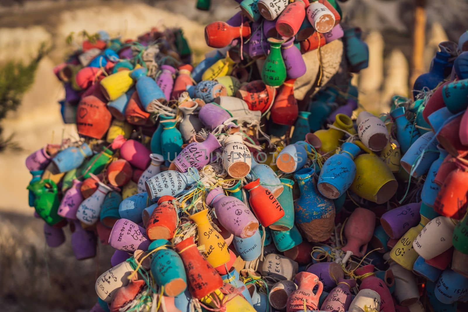 Wish tree. Small multi-colored jugs with inscriptions, wishes hanging on the branches of a tree., against the backdrop of sand ruins and blue sky by galitskaya