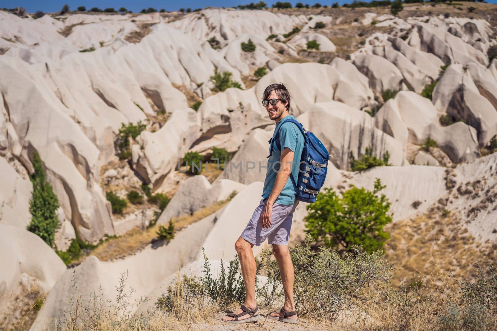 Young man exploring valley with rock formations and fairy caves near Goreme in Cappadocia Turkey.