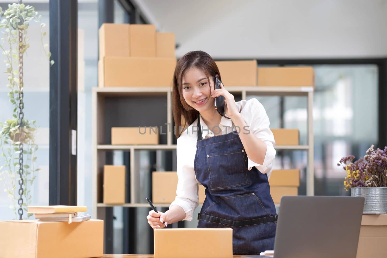 Young Asian Woman Working at home, Young Owner Woman talking to customer and working with happy emotion. People with online shopping SME entrepreneur or freelance working concept...