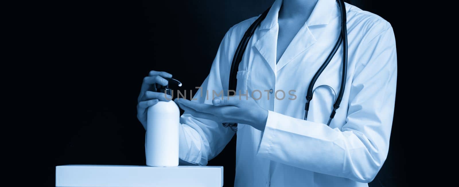 doctor applying antibacterial spray on hand on black background by Mariakray