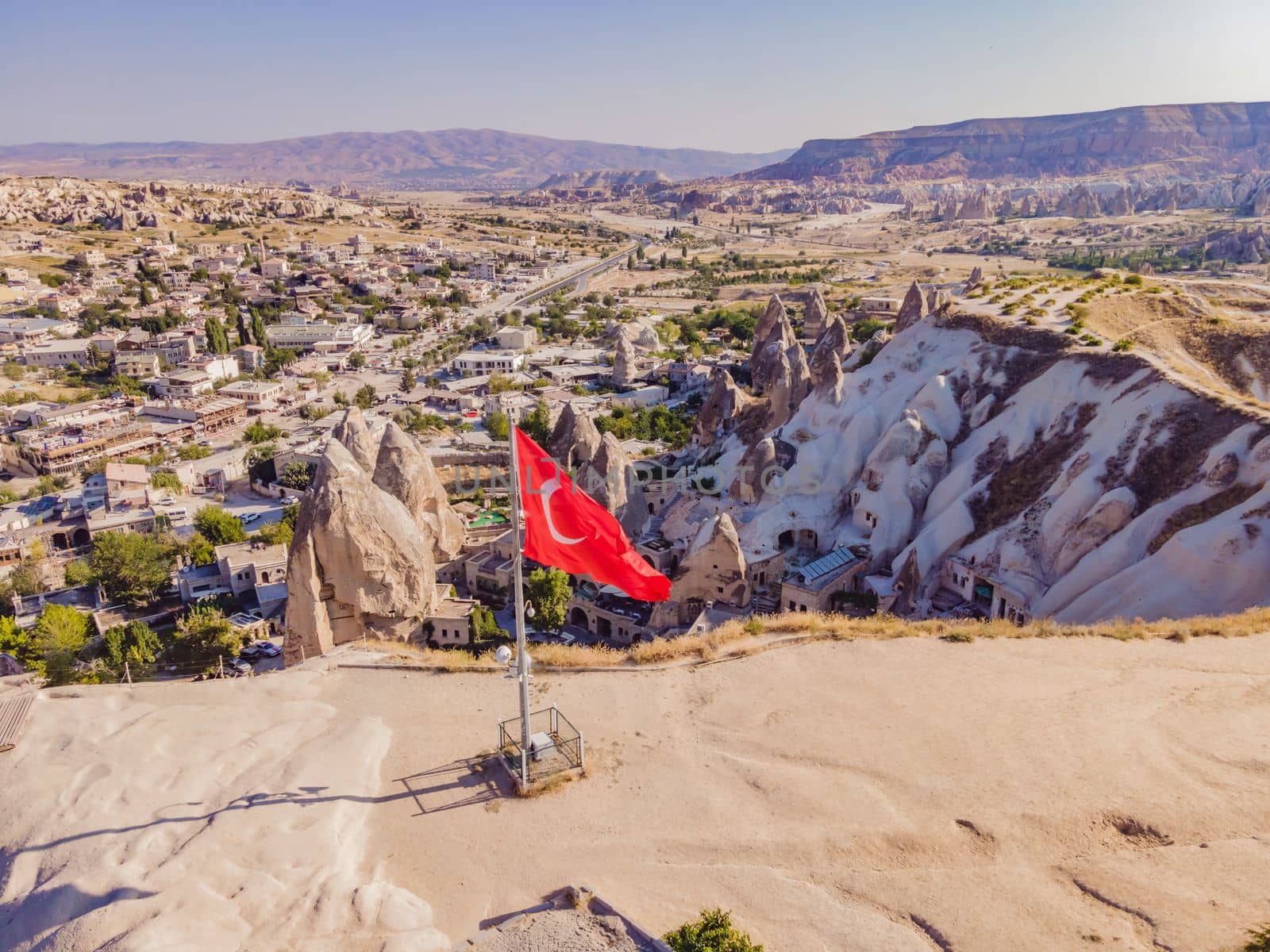 Turkish flag on the hill with typical tuff rock formations of the Cappadocia against the backdrop of a blue sky, Goreme, Turkey by galitskaya