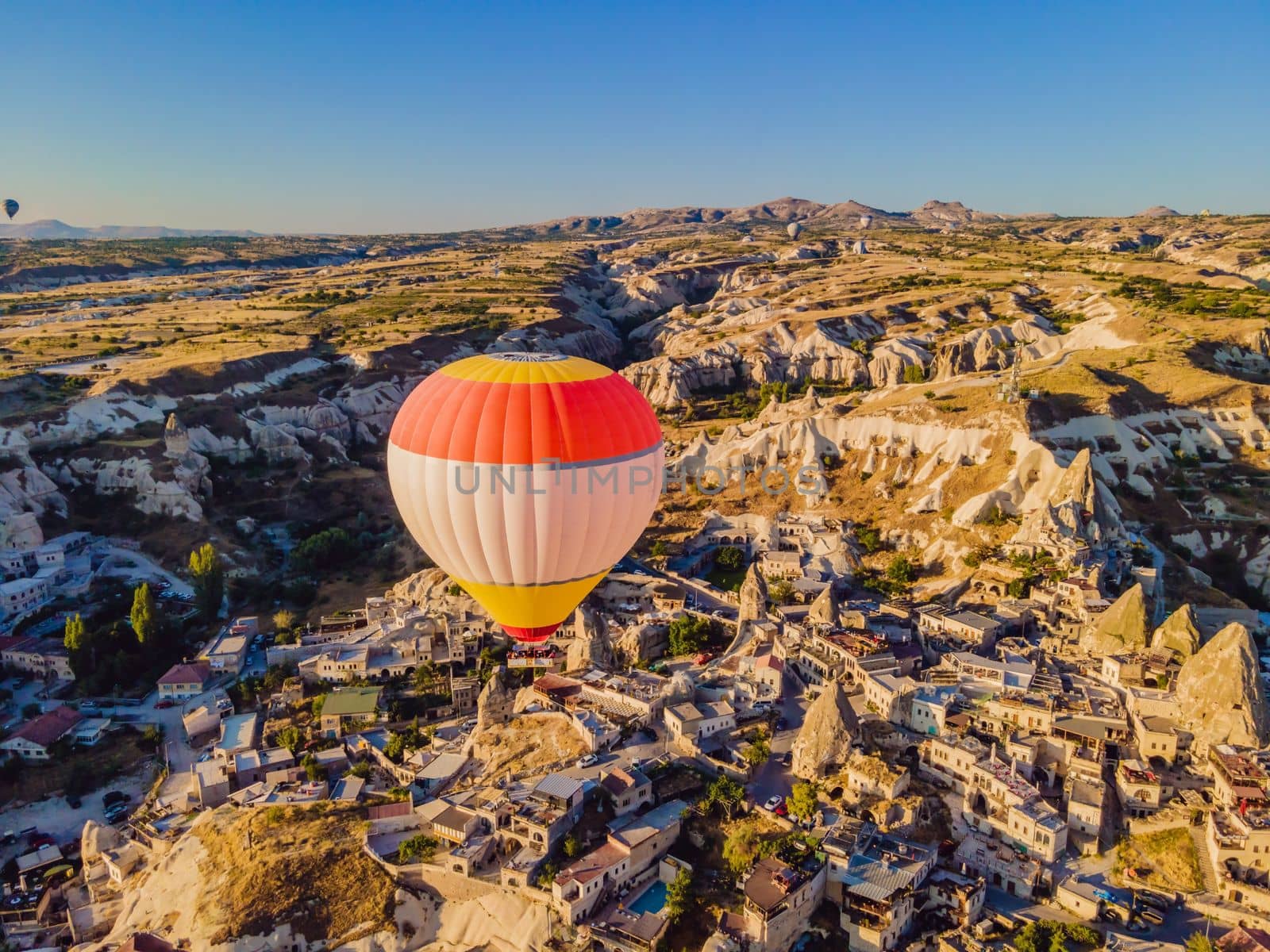 Colorful hot air balloons flying over at fairy chimneys valley in Nevsehir, Goreme, Cappadocia Turkey. Spectacular panoramic drone view of the underground city and ballooning tourism. High quality by galitskaya