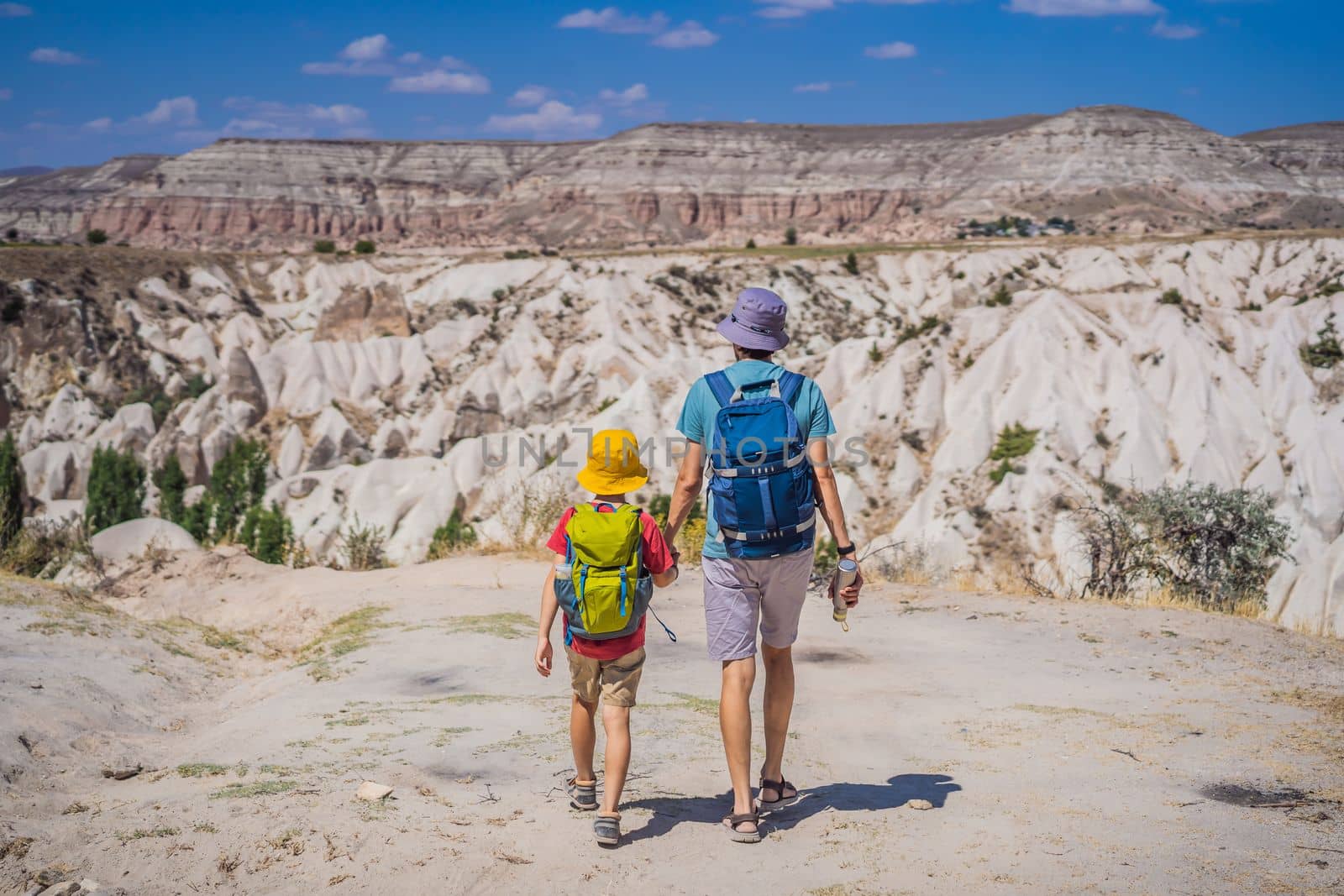 Father and son tourists exploring valley with rock formations and fairy caves near Goreme in Cappadocia Turkey.