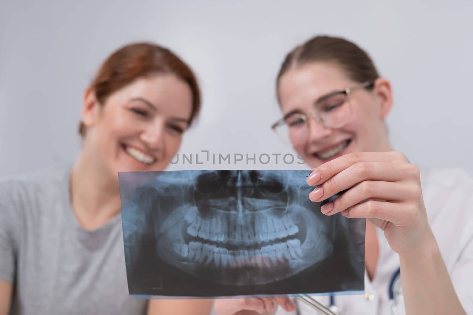 A woman doctor and a patient at the reception are discussing an x-ray of the jaw. by mrwed54