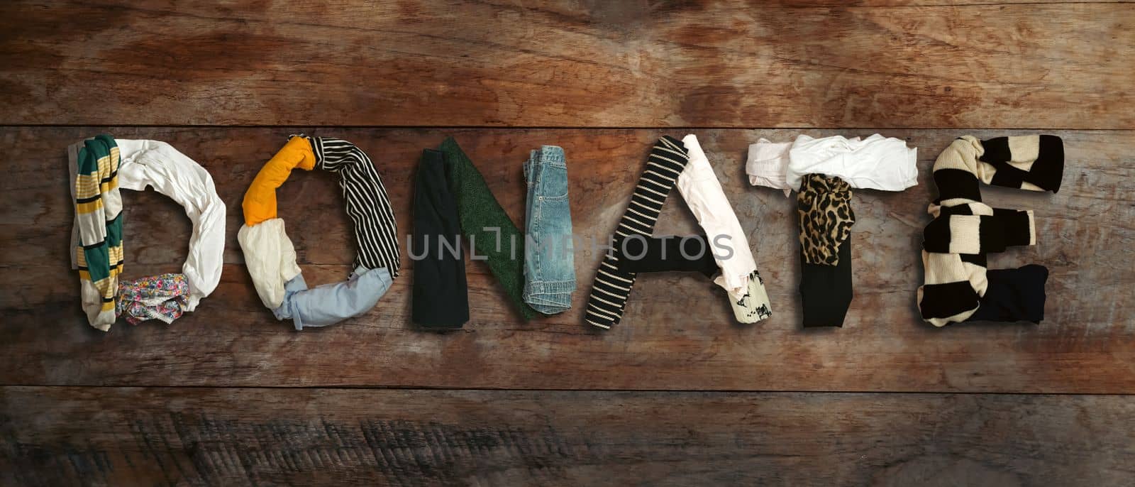 DONATE word made from various clothing on wooden background. Charity, donation and reuse recycle concept.