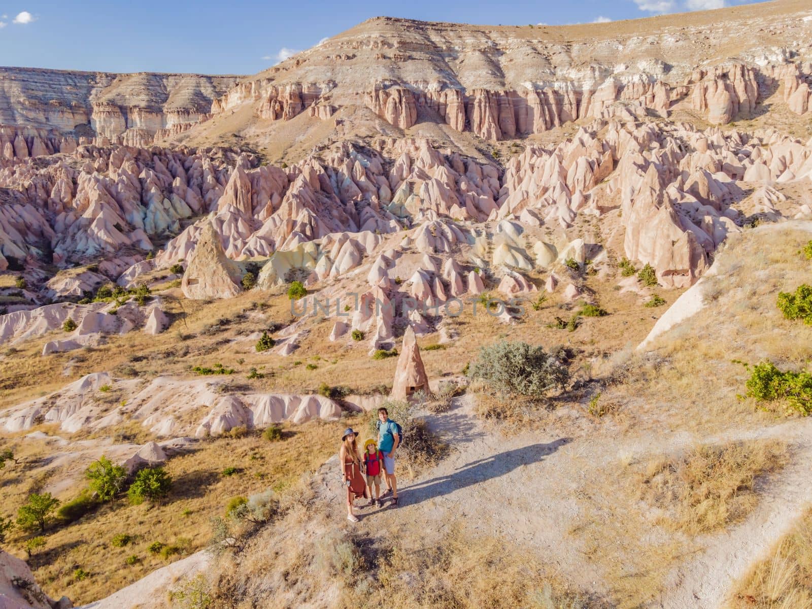 Happy family mother, father and son tourists exploring valley with rock formations and fairy caves near Goreme in Cappadocia Turkey by galitskaya