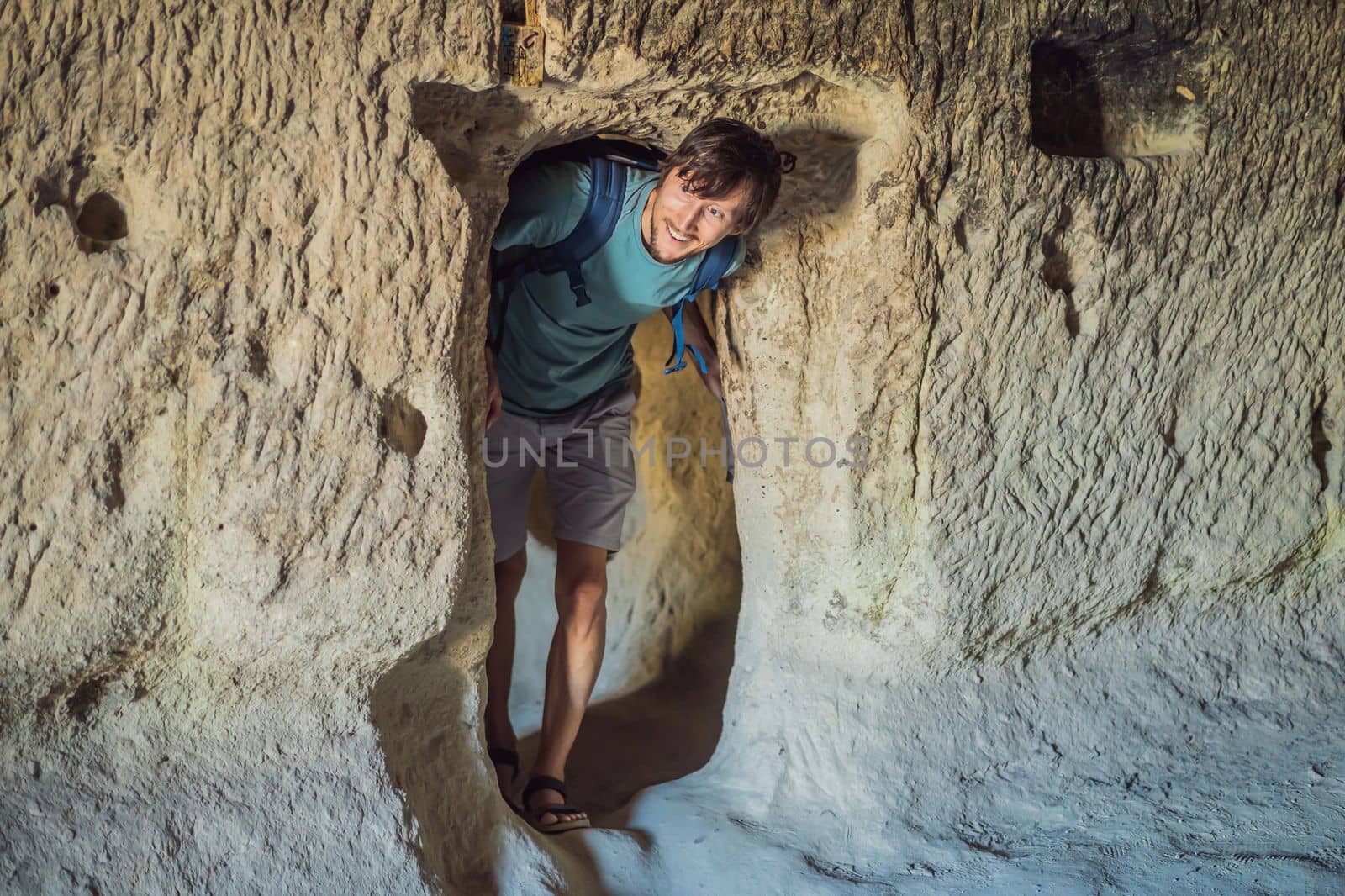 Young man exploring valley with rock formations and fairy caves near Goreme in Cappadocia Turkey.