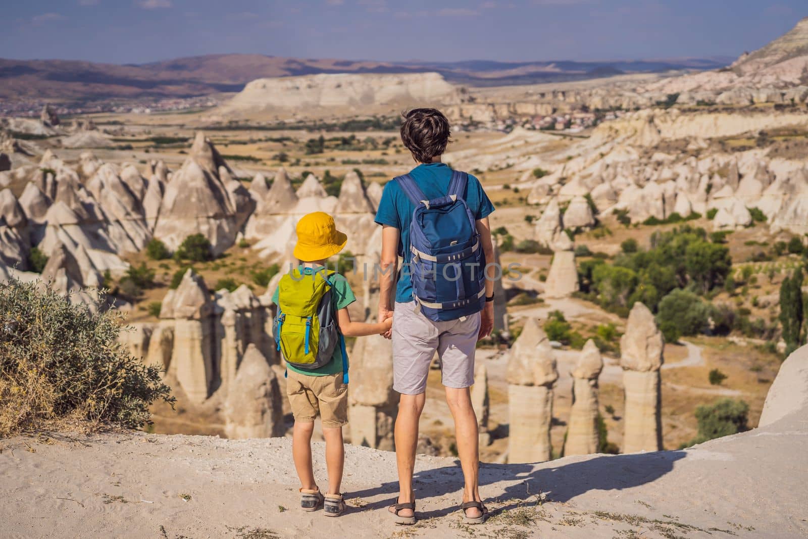 Father and son tourists exploring valley with rock formations and fairy caves near Goreme in Cappadocia Turkey.