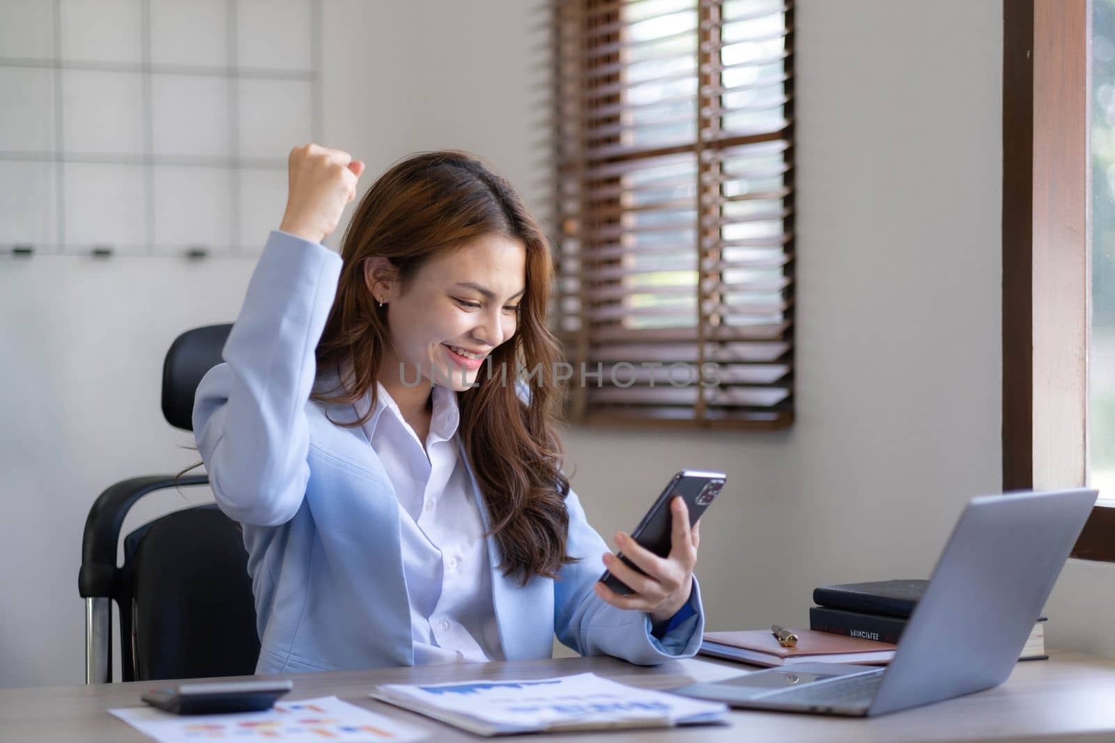 Portrait of an excited young asian girl using laptop computer and celebrating success for online...