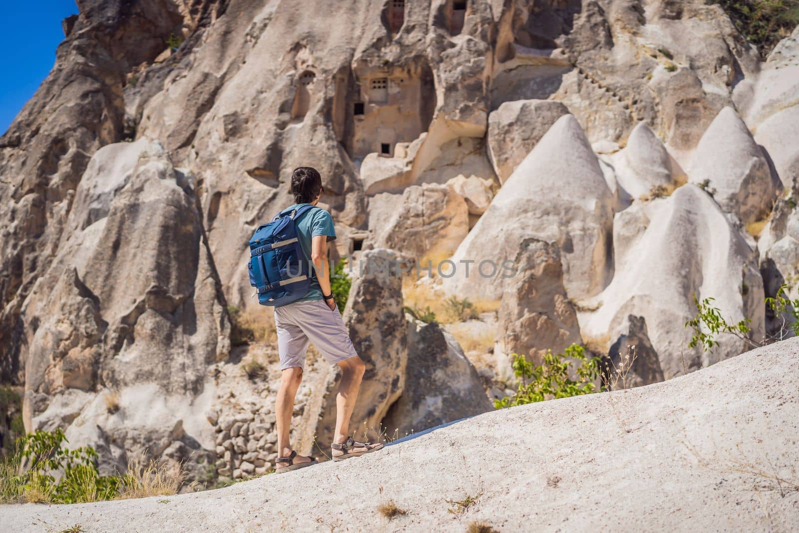 Young man exploring valley with rock formations and fairy caves near Goreme in Cappadocia Turkey.