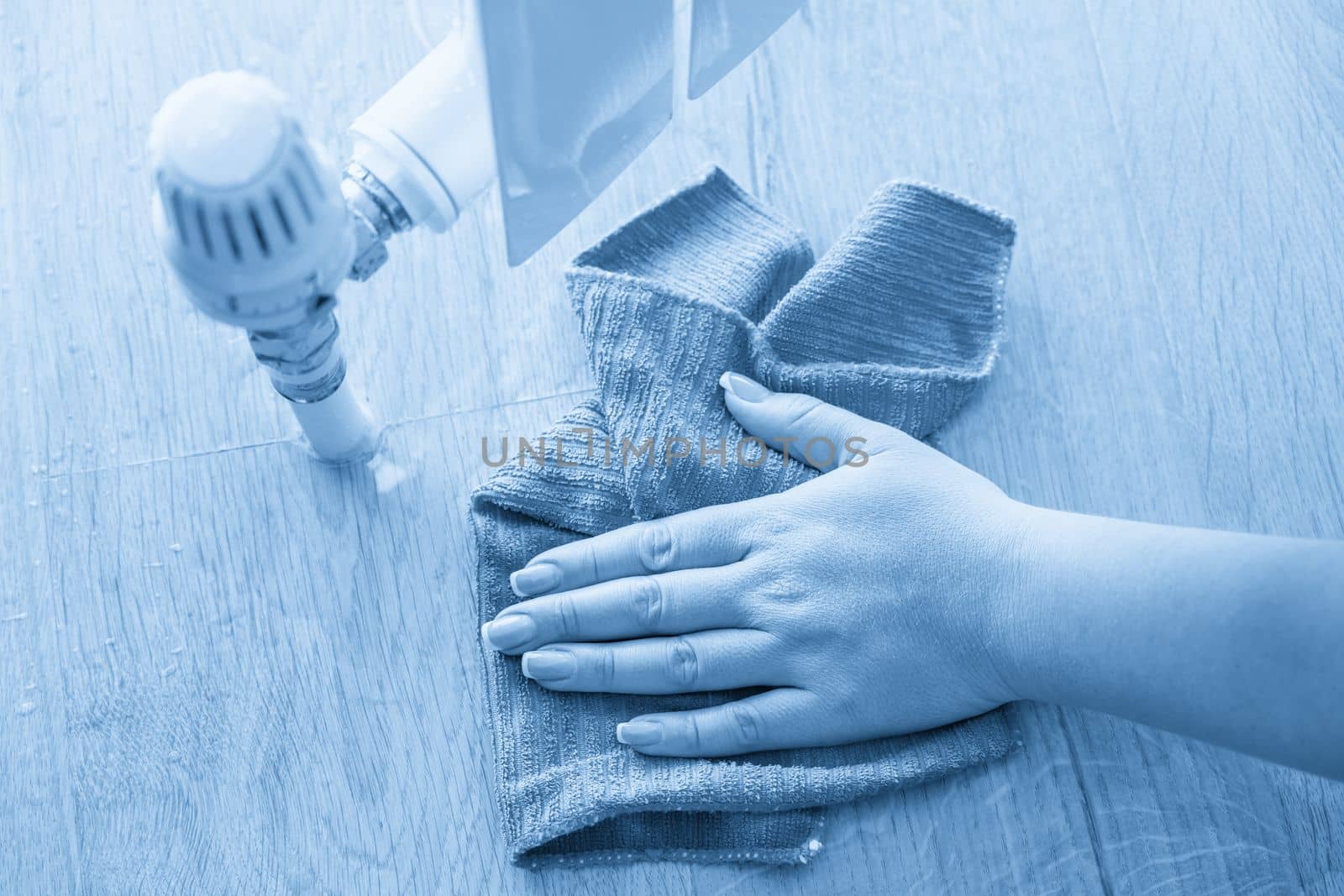 Female hand with rag cleaning water from heating radiator