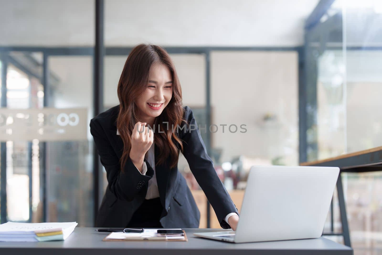 Successful Asian business woman achieving goals. Excited woman screaming with laptop.