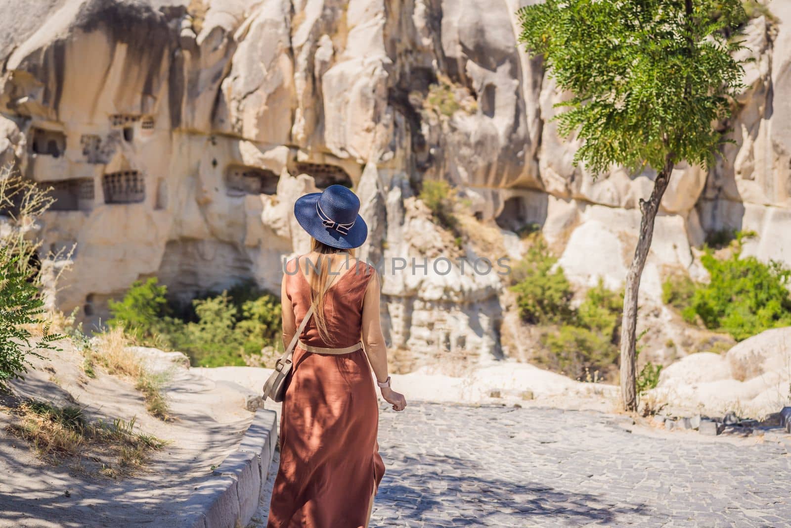 Young woman exploring valley with rock formations and fairy caves near Goreme in Cappadocia Turkey.