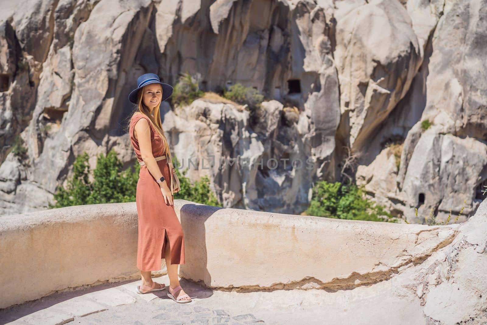 Young woman exploring valley with rock formations and fairy caves near Goreme in Cappadocia Turkey.