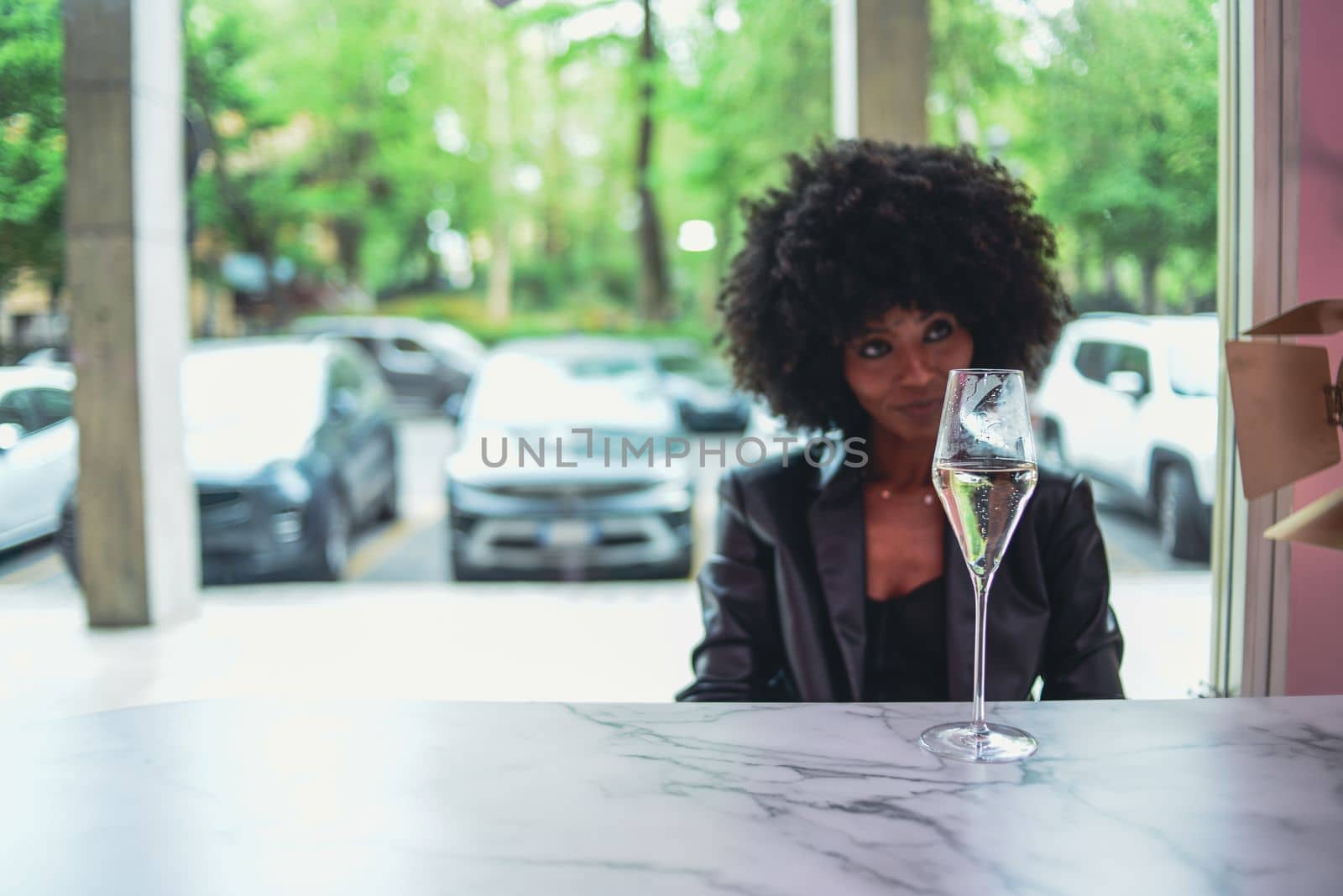 Young attractive African woman with happy cheerful smile drinking and having fun in a bar