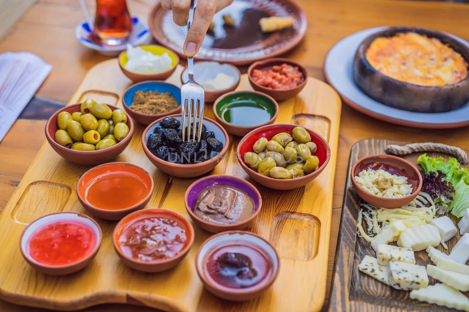 Turkish breakfast table. Pastries, vegetables, greens, olives, cheeses, fried eggs, spices, jams, honey, tea in copper pot and tulip glasses, wide composition by galitskaya