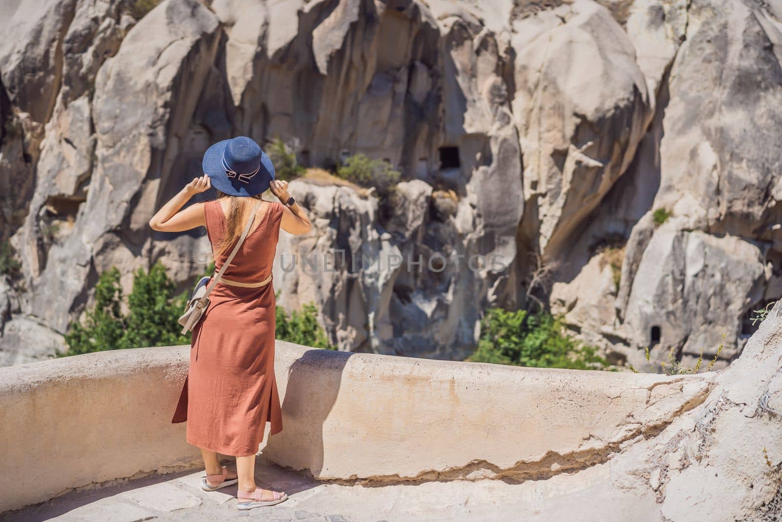 Young woman exploring valley with rock formations and fairy caves near Goreme in Cappadocia Turkey.