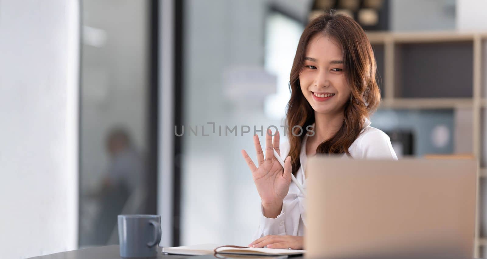 Asian woman working in office and discussing with business partner via laptop video call, young Asian business woman is business executive, founding startup executive. Startup business concept...