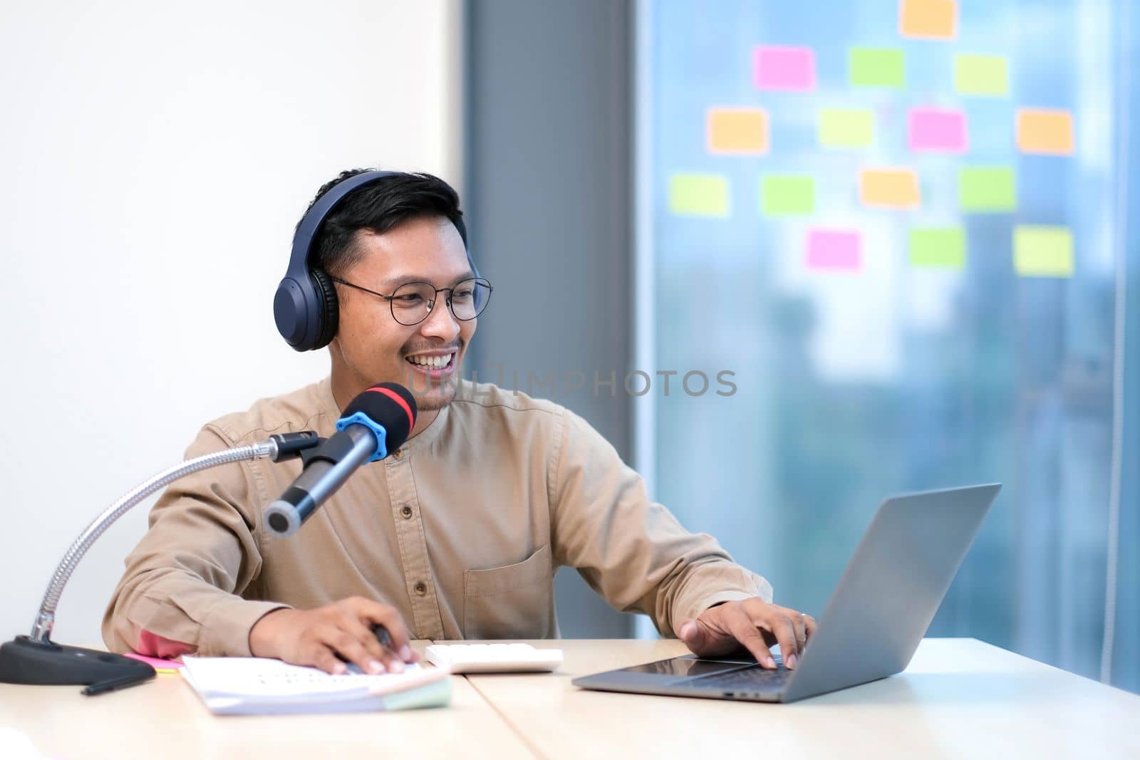 Young man recording podcast using microphone and laptop happy face smiling Positive person