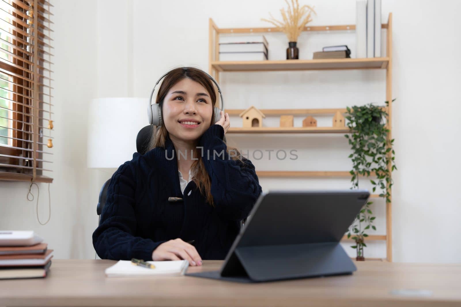 smiling girl relaxing at home She is listening to music using her laptop and wearing white headphones