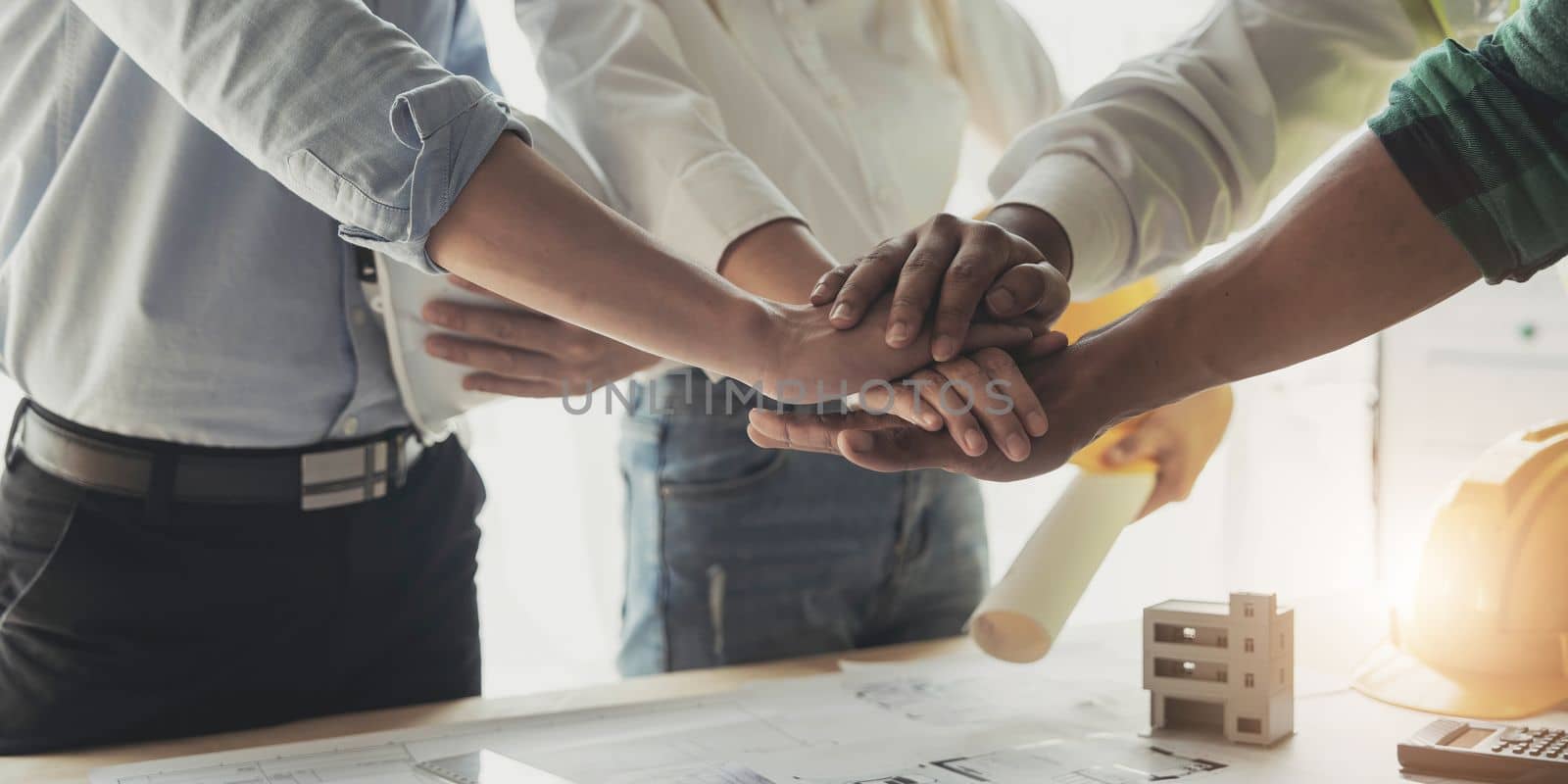 Businessmen and engineers join hands to build successful projects. Teamwork concept...