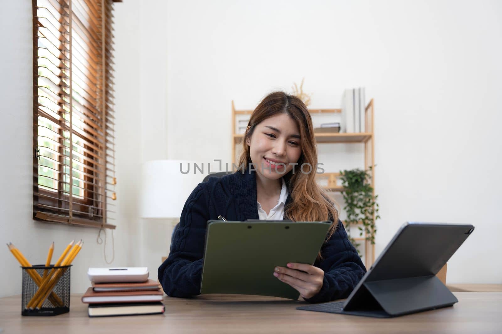 Asian woman Using laptop computer and working at office with calculator document on desk, doing planning analyzing the financial report, business plan investment