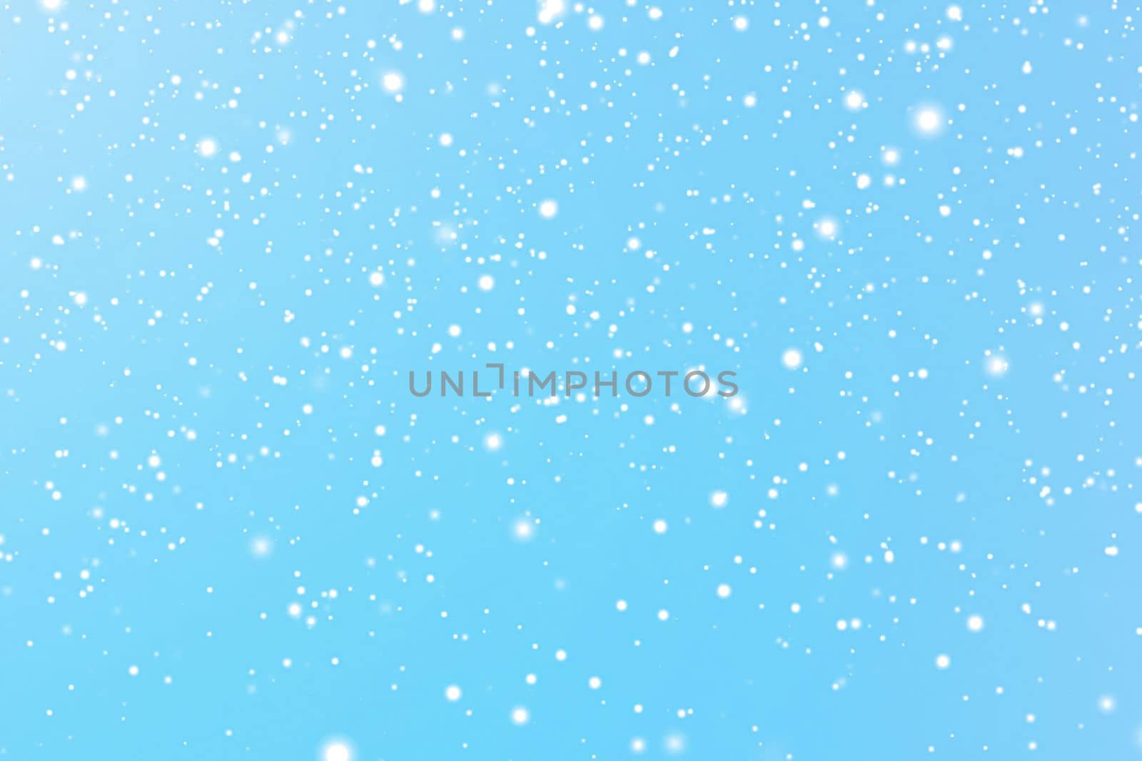 Winter holidays and wintertime background, white snow falling on blue backdrop, snowflakes bokeh and snowfall particles as abstract snowing scene for Christmas and snowy holiday design. High quality 4k footage