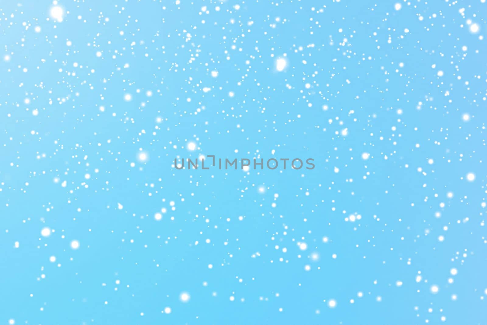 Winter holidays and wintertime background, white snow falling on blue backdrop, snowflakes bokeh and snowfall particles as abstract snowing scene for Christmas and snowy holiday design. High quality 4k footage