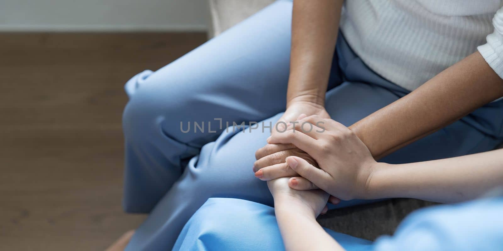 Happy patient is holding caregiver for a hand while spending time together. Elderly woman in nursing home and nurse. by wichayada