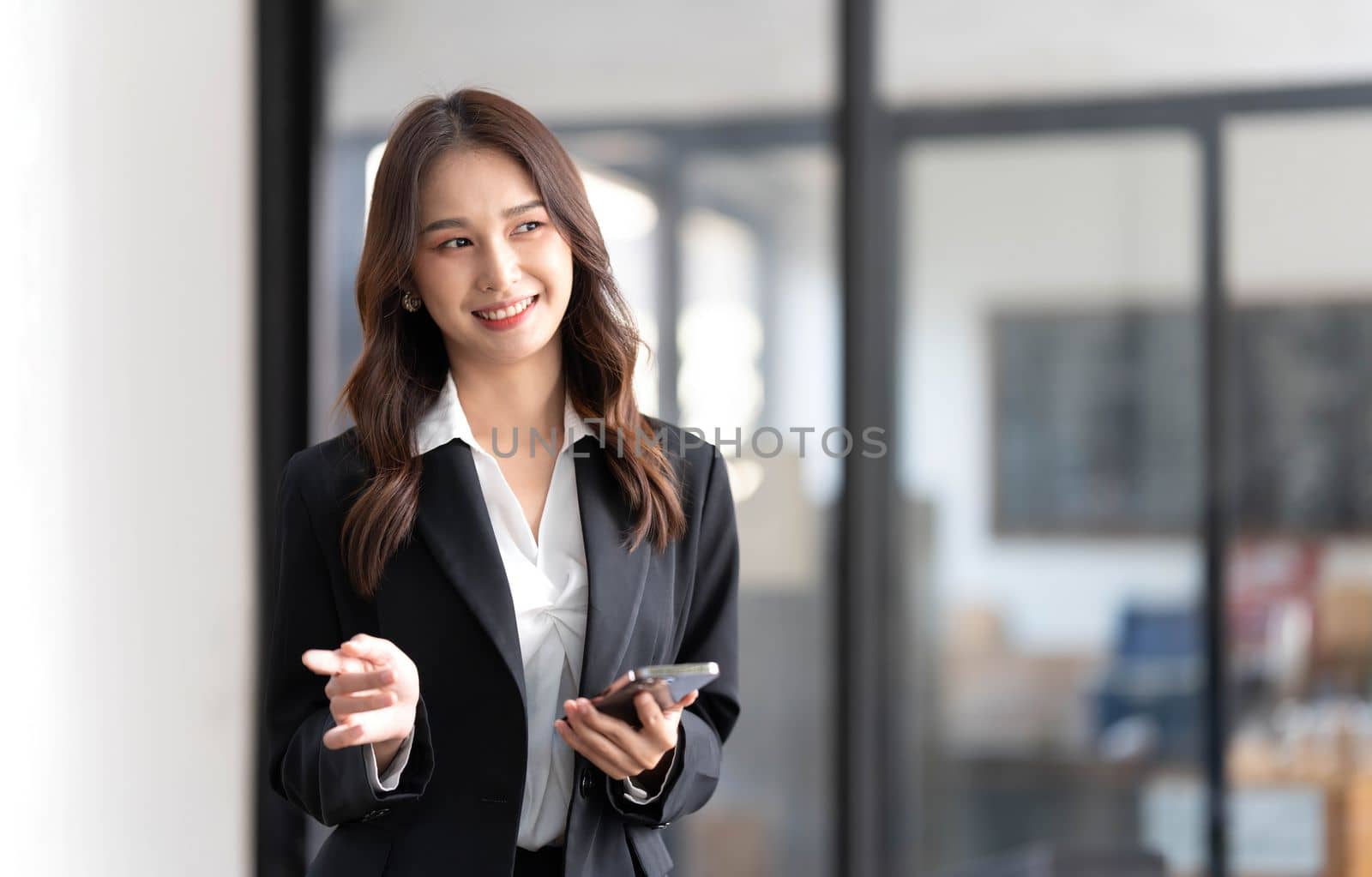 Image of a young Asian businesswoman standing using mobile phone at the office...