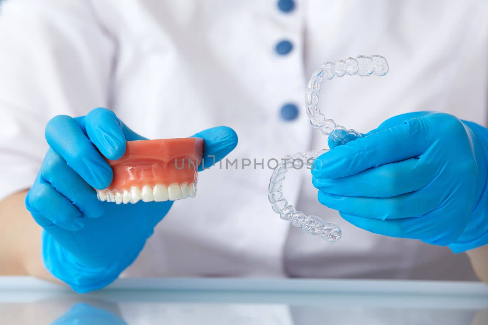 Orthodontist showing how the system of transparent aligners works on an artificial jaws