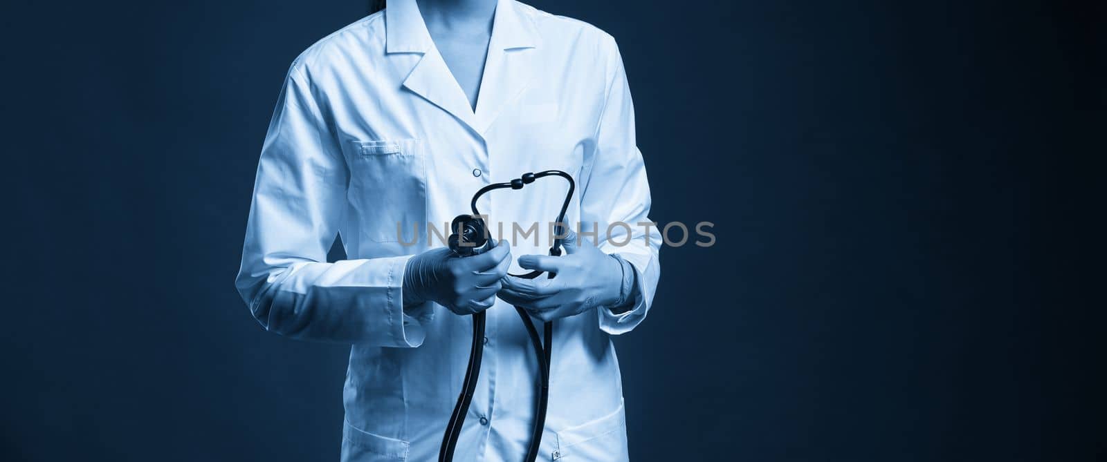 Young doctor with stethoscope against black background, studio shot with copy space by Mariakray