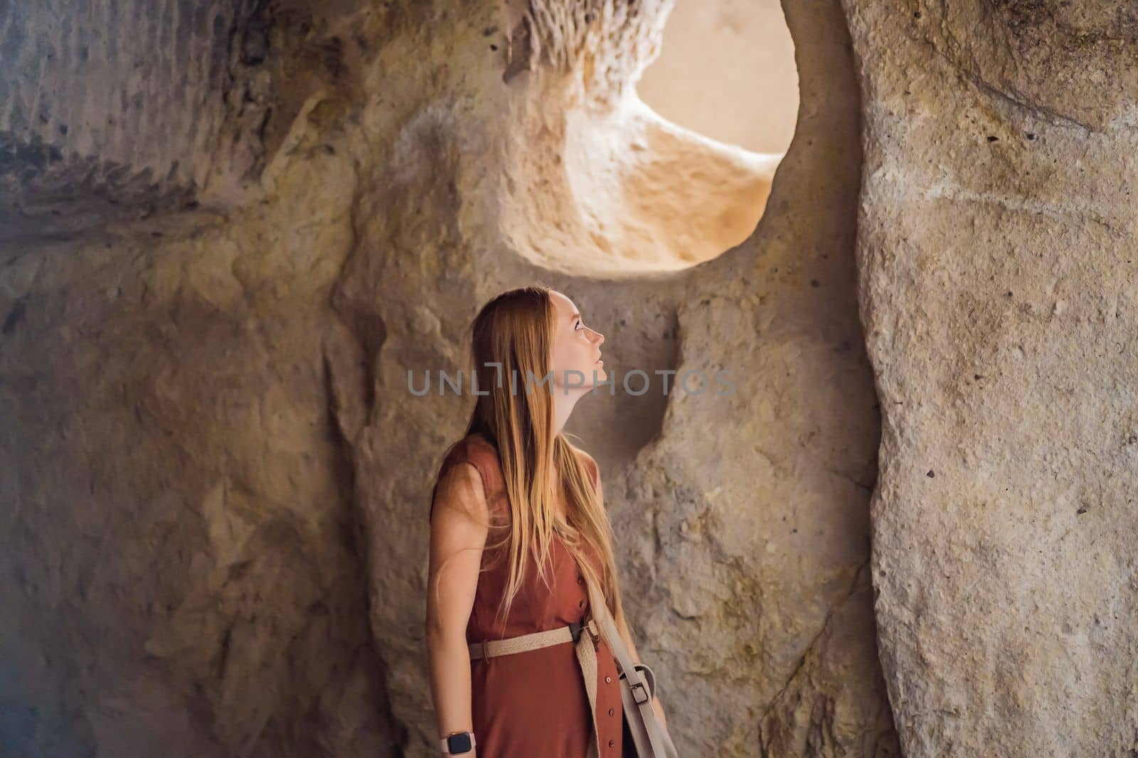 Young woman exploring valley with rock formations and fairy caves near Goreme in Cappadocia Turkey.