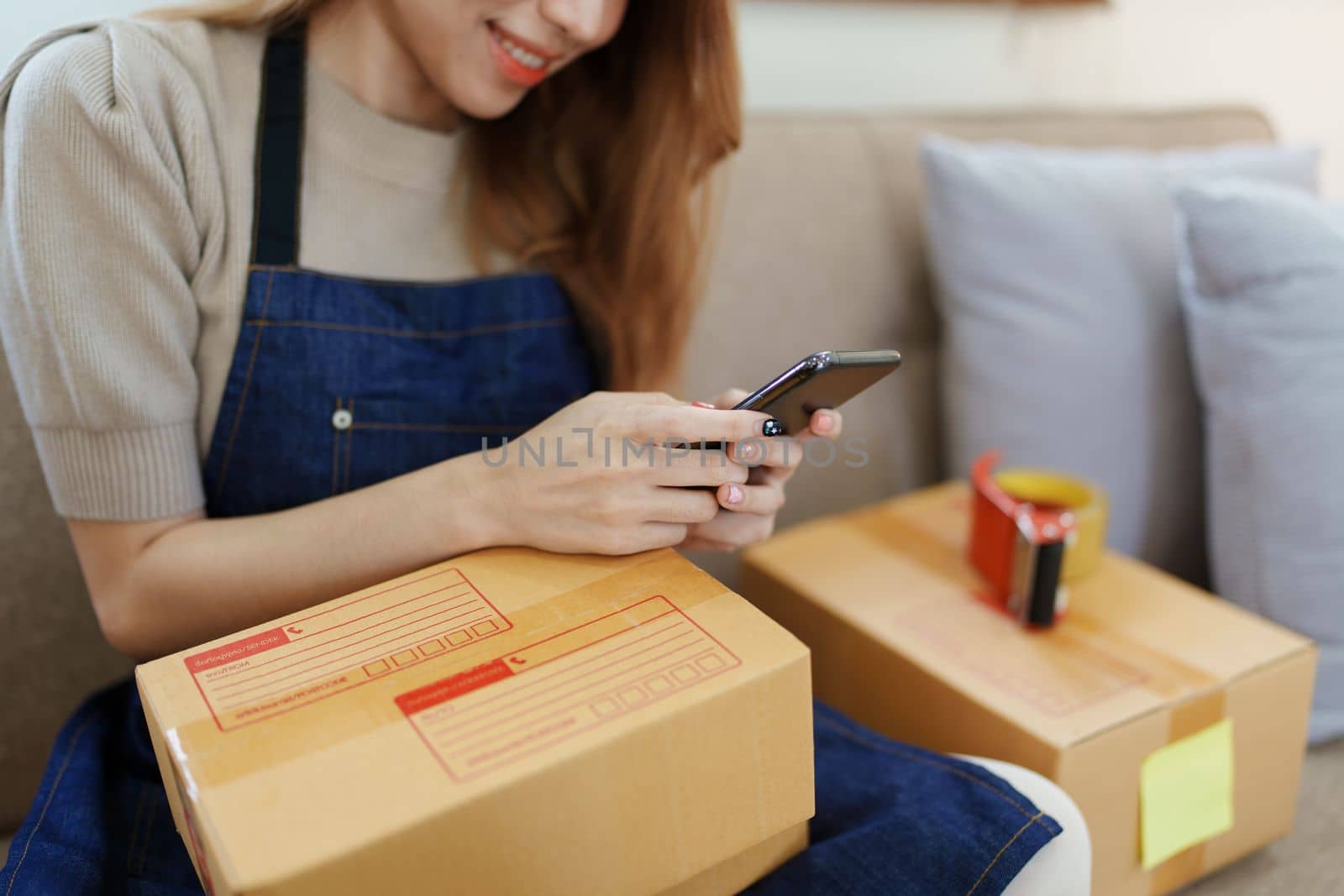 Starting small business entrepreneur of independent Asian woman smiling using computer laptop with cheerful success of online marketing package box items and SME delivery concept by Manastrong