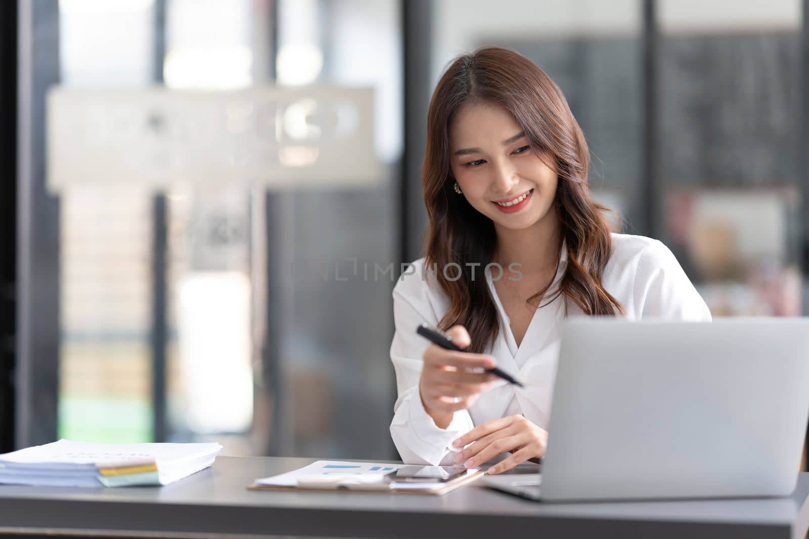 Young beautiful asian businesswoman working on tablet with happiness while sitting at the table in modern office room...