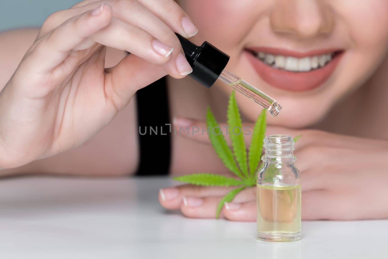 Young charming girl applying CBD serum from cannabis extracted oil for skincare. by biancoblue
