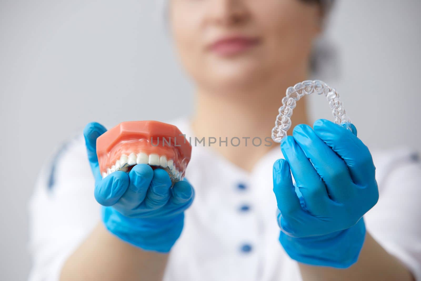 Doctor orthodontist showing model of human jaw with wire braces and aligners explaining difference