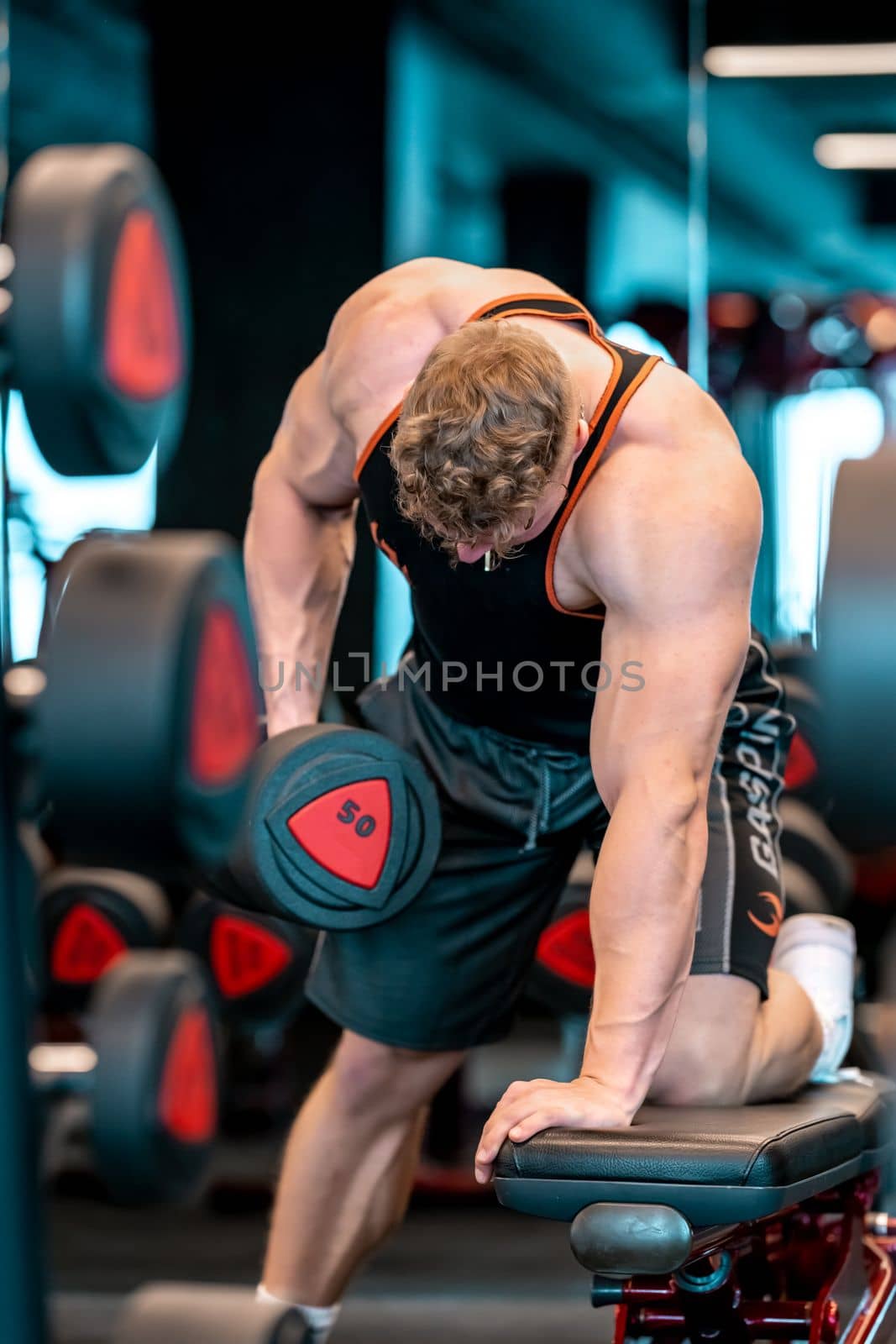 one-handed dumbbell pull-ups in a forward bend on a bench. High quality photo