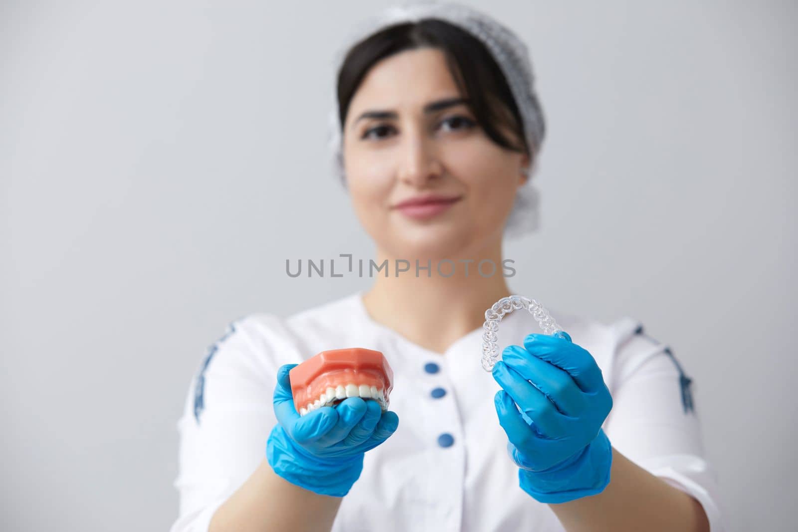 Dentist showing model of human jaw with wire braces and aligners to compare by Mariakray