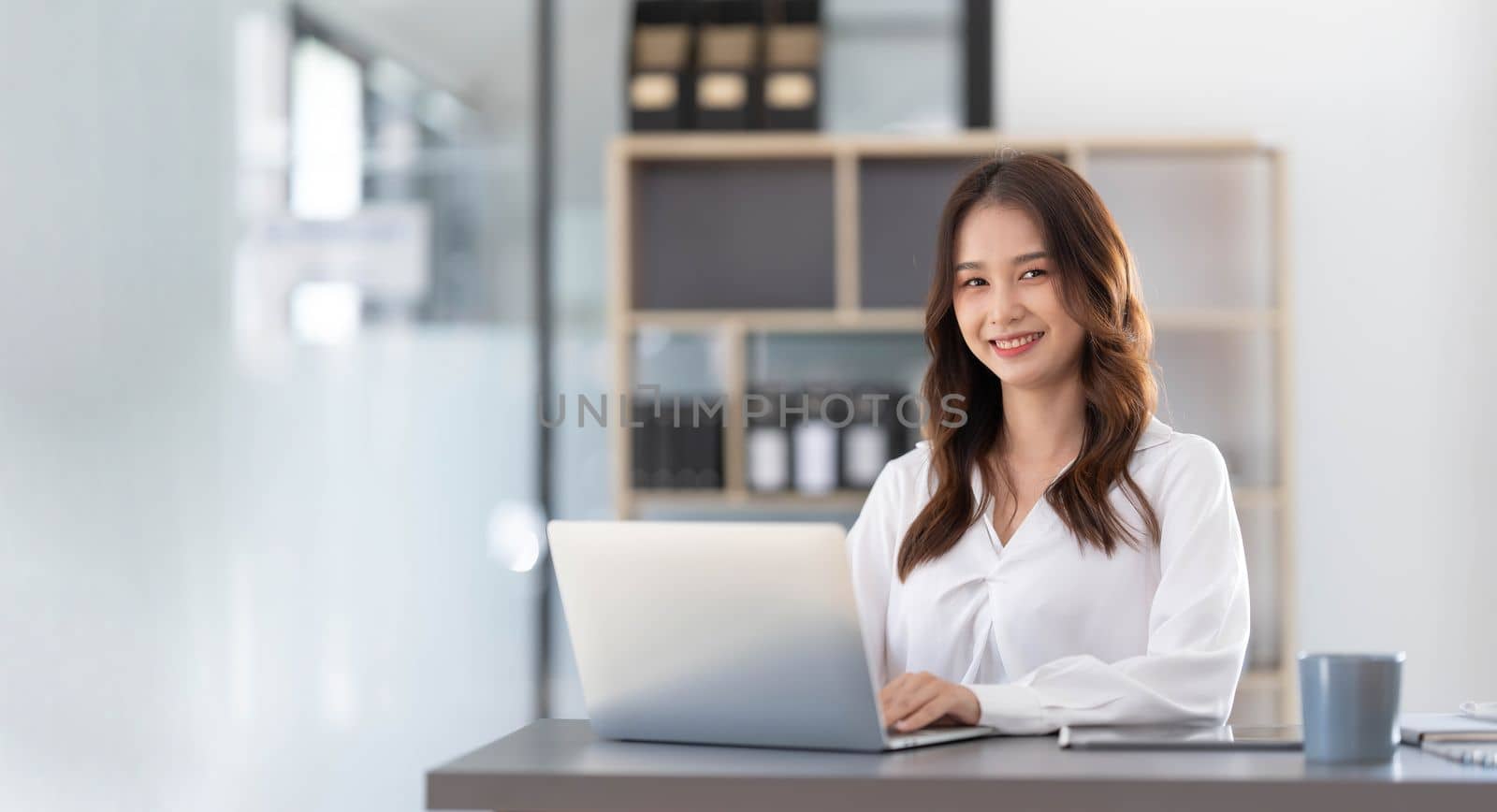 Charming Asian woman working at the office using a laptop Looking at the camera...