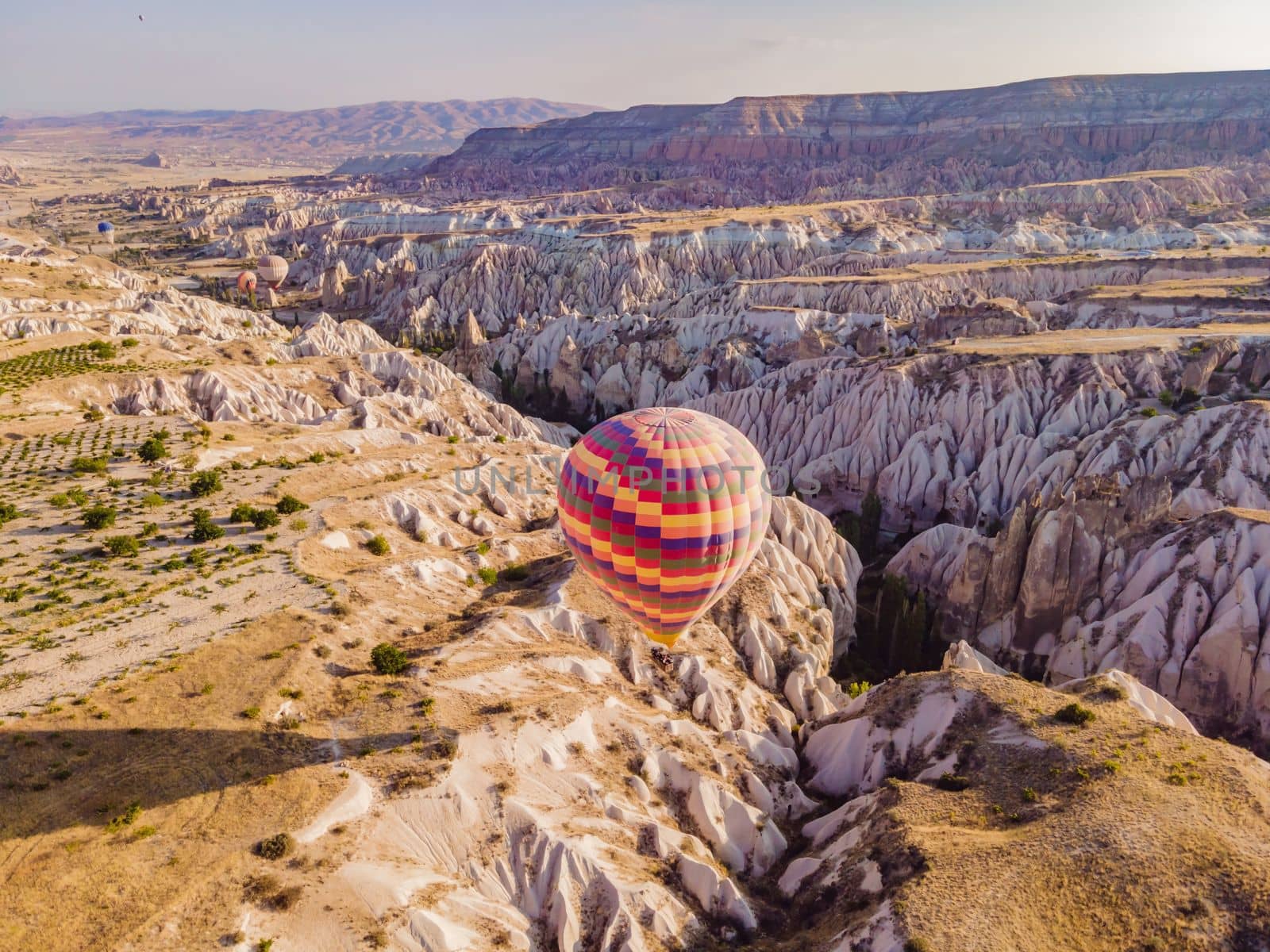 Colorful hot air balloons flying over at fairy chimneys valley in Nevsehir, Goreme, Cappadocia Turkey. Spectacular panoramic drone view of the underground city and ballooning tourism. High quality by galitskaya