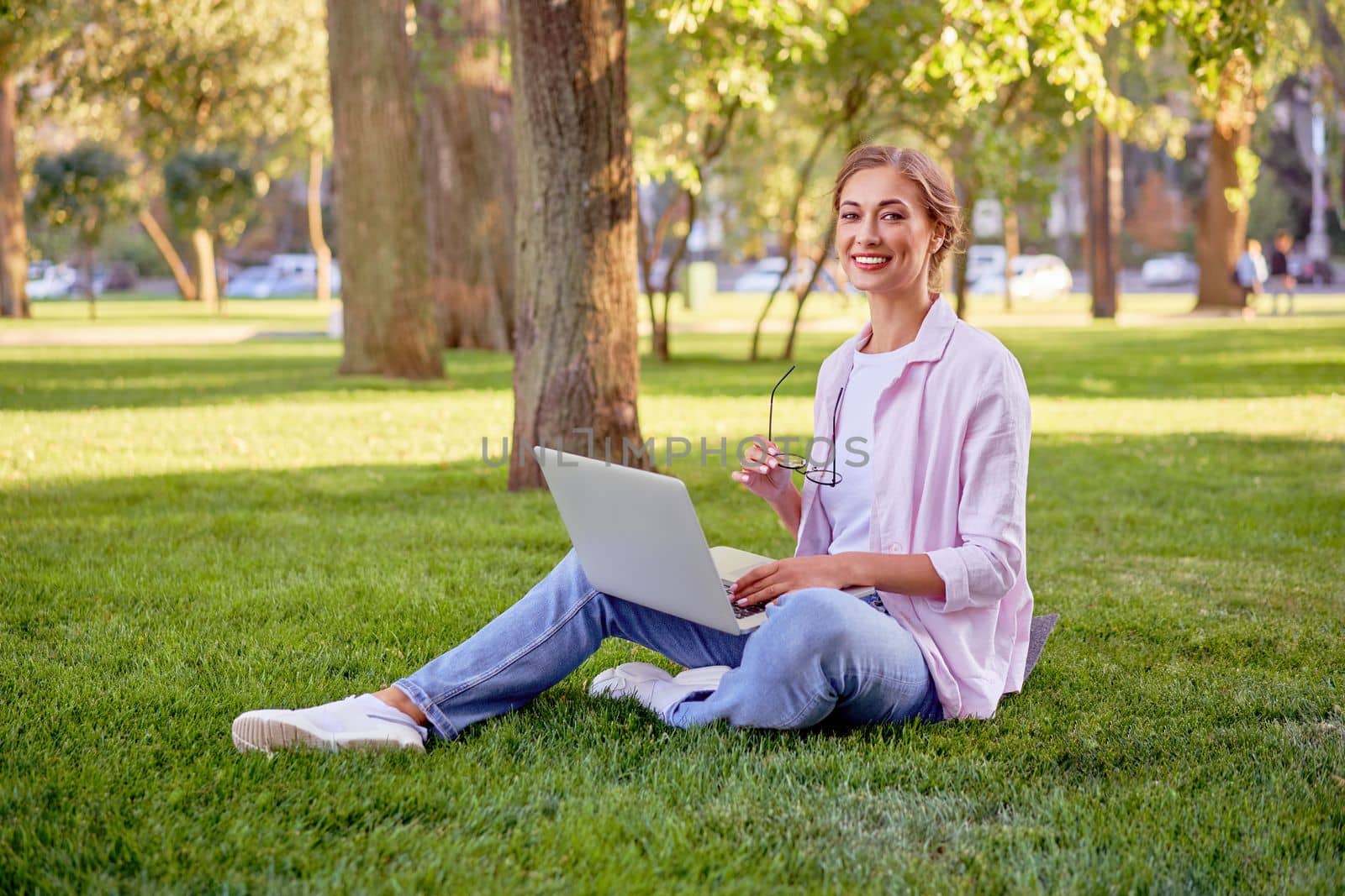 Businesswoman sitting grass summer park using laptop Business person working remote. Outdoor Successful european caucasian woman freelancer make video call teacher study work online lessons