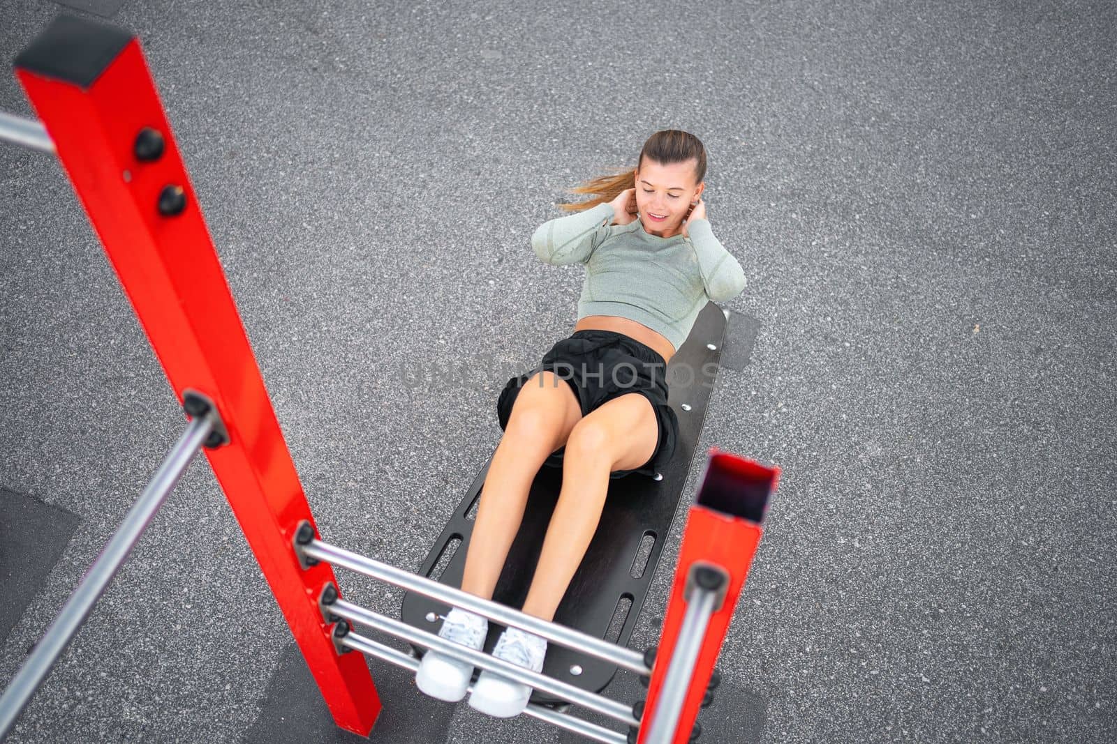 Sit-ups exercises. Active, fit sporty woman doing situps, exercising and training on fitness outdoor gym. One young, serious and athletic female exercising, working out and doing physical activity